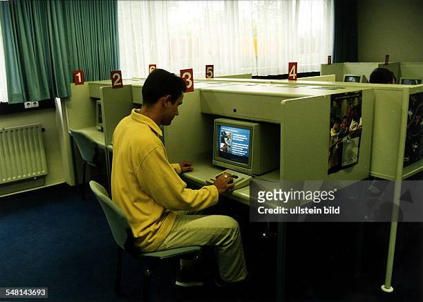 Junger Mann in einem Arbeitsamt. Er ruft Informationen über verschiedene Berufe per Video ab. - 1996
