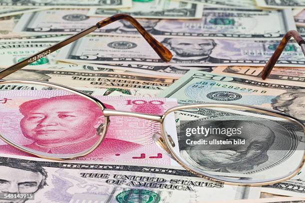 Chinese Yuan Renminbi with portrait of Mao Zedong and Dollar banknotes with portrait of George Washington, seen through glasses