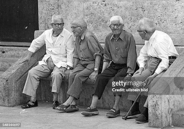 People, older people, four older men sit on a bench, gossip, walking stick, aged 70 to 80 years, Spain, Valencia -