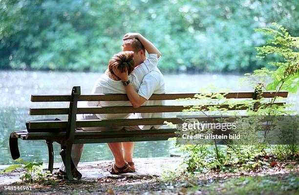 Liebespaar küsst sich auf einer Parkbank