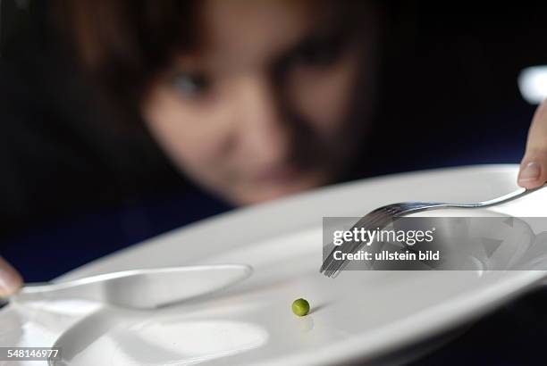 Woman is eating one pea lying on a plate -