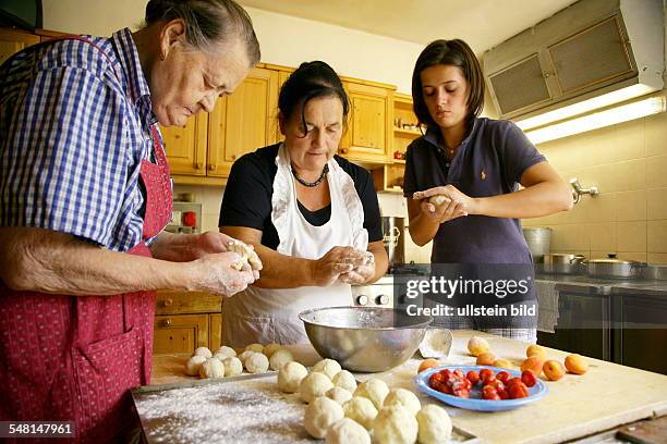 Italy - Signat: Baumann farm of the Hoeller family, grandmother, mother and doughter are preparing Marillenknoedel, traditional dumplings with...