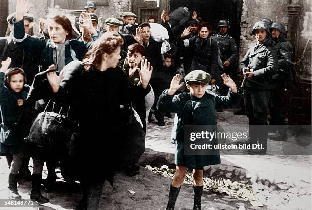 Group of Jewish civilians being held at gunpoint by German SS troops after being forced out of a bunker where they were sheltering during the Warsaw...