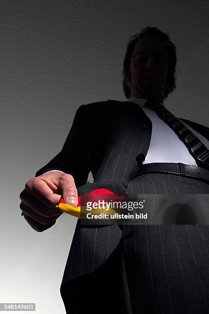 Symbolic photo: national bankruptcy of Germany, high taxes, Man in a suit with empty pockets in the national colours of Germany