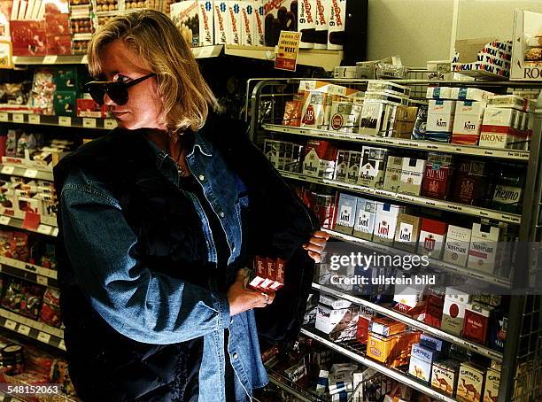 Symbolfoto Ladendiebstahl. Kundin klaut Zigaretten in einem Supermarkt - 1996