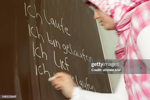 Germany Berlin - school girl is writing at the blackboard