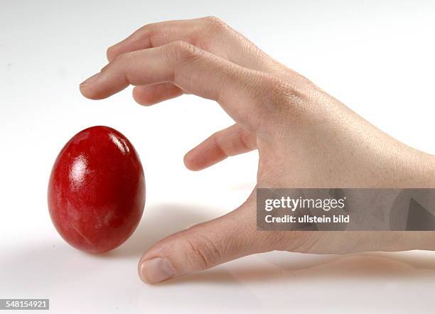 Hand is taking a red Easter egg