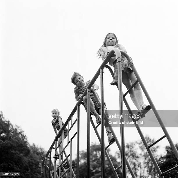 People, children, little girl and two boys on a monkey bars, childrens playground, aged 4 to 7 years -