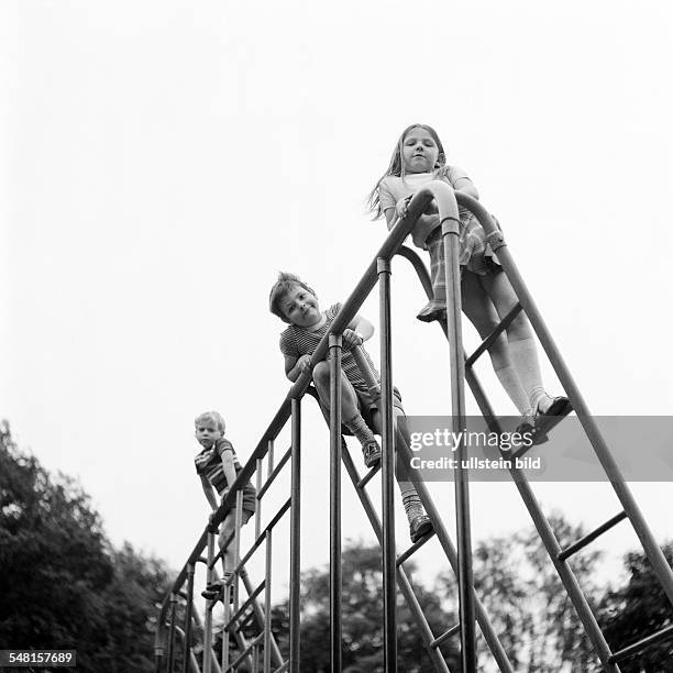 People, children, little girl and two boys on a monkey bars, childrens playground, aged 4 to 7 years -
