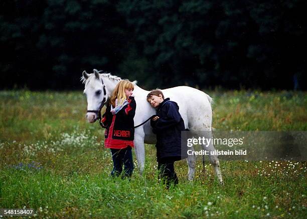 Mädchen und Junge mit einem Pony auf einer Wiese - 1998