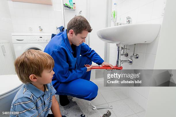 Boy is watching a plumber doing his work -