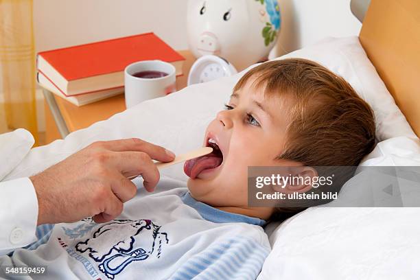 Sick boy in bed, doctor is examining the child -