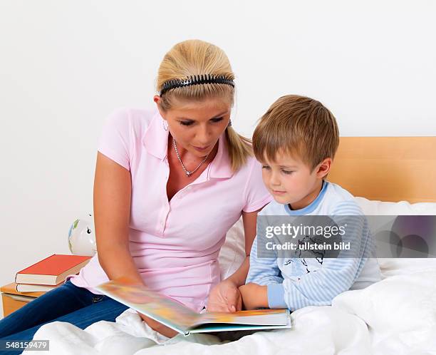 Mother and child reading a book in bed -