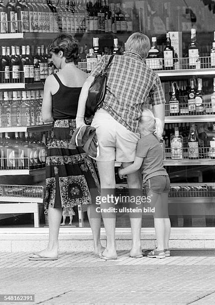 People, family, parents on a shopping expedition with the little daughter stand near a shopwindow of a drinks cash-and-carry, tourists, man, aged 30...