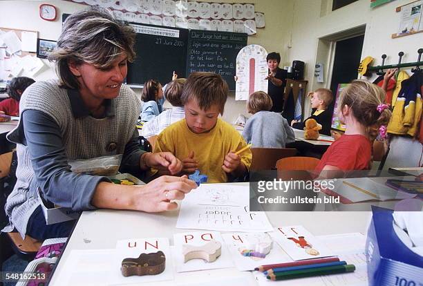 Behindertes Mädchen mit Down-Syndrom im Unterricht in einer Integrationsklasse der Picasso - Grundschule in Weissensee; Lehrerin zeigt dem Kind die...