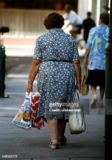 Ältere Frau schleppt Einkaufstüten und eine Tasche - 1997