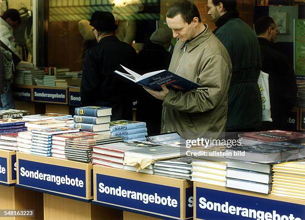 Ein Kunde blättert in einem Buch an einem Stand mit Sonderangeboten einer Buchhandlung - 2000