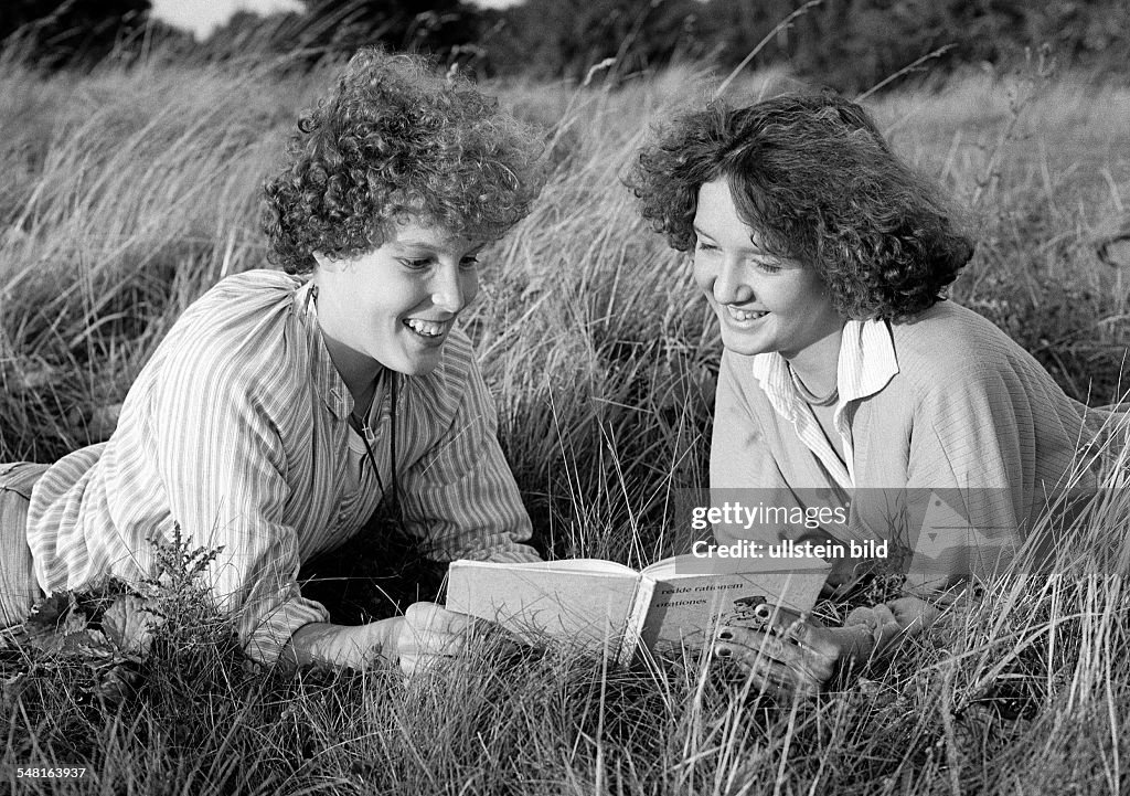 People, two young girls lie in the grass reading jointly in a book, blouse, pulli, aged 16 to 20 years - 30.09.1978