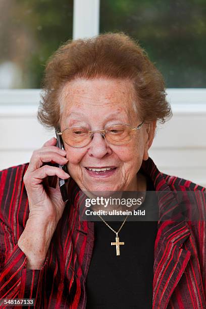 Elderly woman is having a phone call with mobile phone -