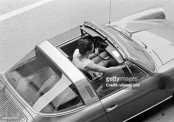 Road traffic, young woman sits in a Porsche Targa with opened sunroof, birds-eye view, aged 20 to 30 years -