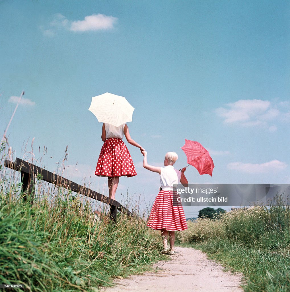 Germany - : two young women with sunshades walking - 01.07.1955