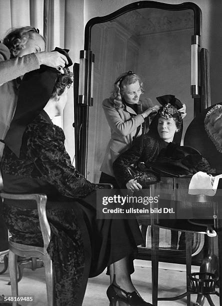 Mrs von Wülfing trying on a hat in the salon of Berlin modiste and hatter Madame Berthe - 1941 - Photographer: Regine Relang - Published by: 'Die...