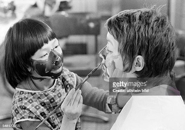 People, physical handicap, school lessons, fostress and a boy from Vietnam paint their faces with a paintbrush each other, aged 20 to 25 years, aged...