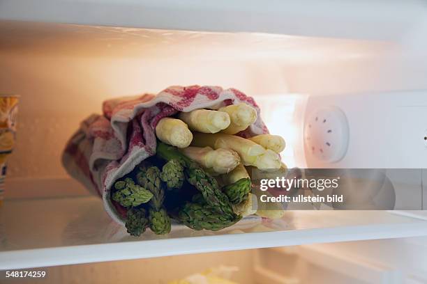 White and green asparagus covered with a wet cloth in a refrigerator