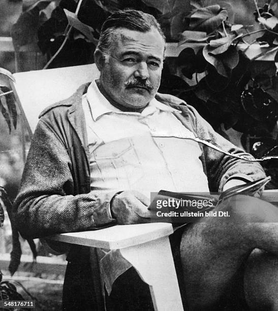Hemingway, Ernest *21.07.1899-+ Writer, USA Winner of the nobel prize for literature 1954 - sitting outdoors in a chair, reading - undated - Vintage...