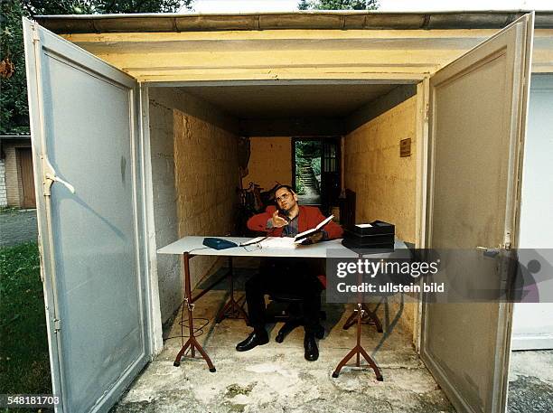 Symbolfoto Existenzgründung, Selbständigkeit: Jungunternehmer sitzt an seinem Schreibtisch in einer Garage - 1999