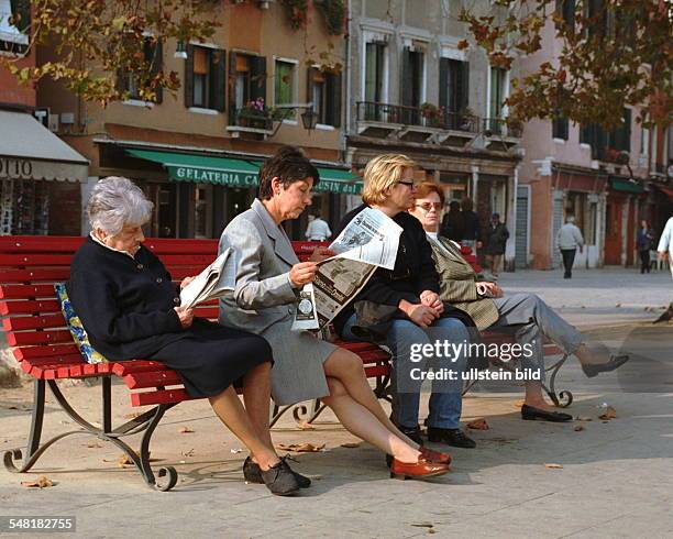 Lesende Frauen sitzen auf einer Bank in Venedig.