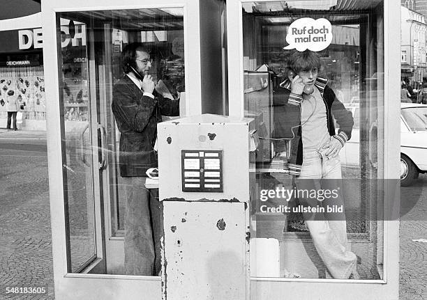 People, communication, a man and a teenager phone from two telephone boxes located side by side, in front stands a letterbox, man, aged 30 to 40...