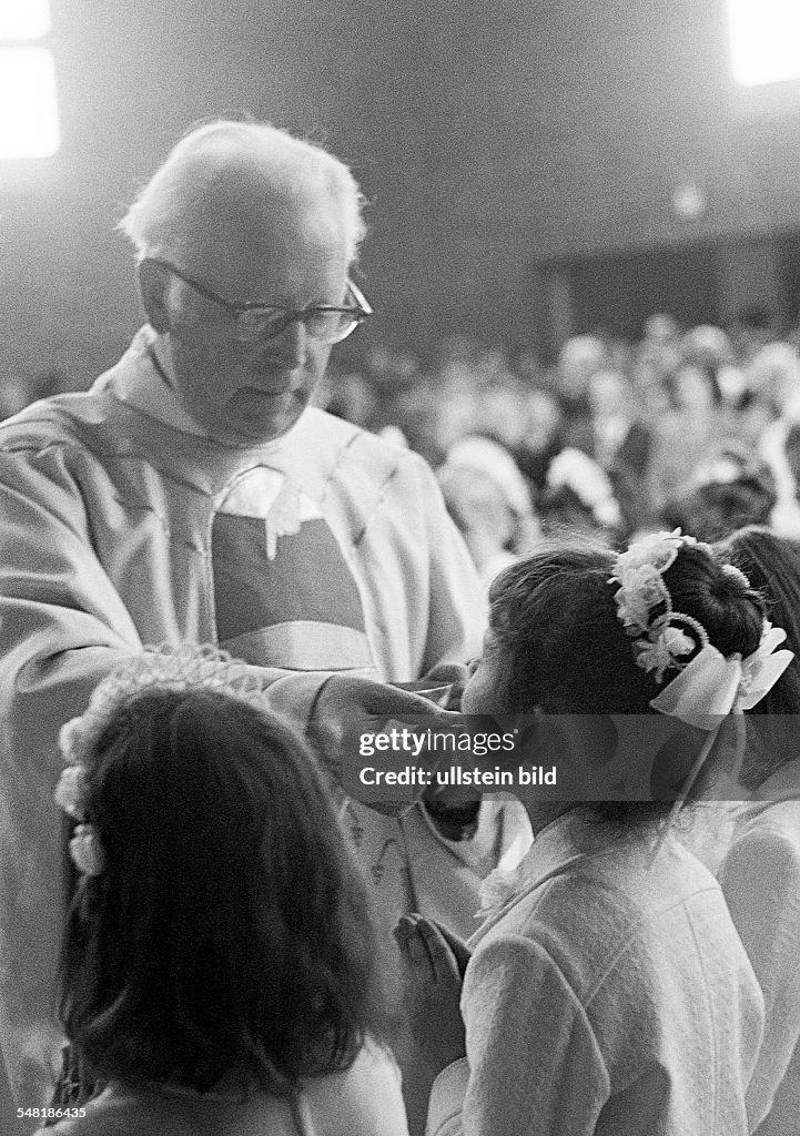 Religion, Christianity, First Communion, Eucharistic mass, priest administers the Holy Communion to a girl, aged 8 to 12 years, aged 55 to 65 years, Babette - 21.04.1974