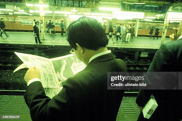 Junger Mann liest Zeitung auf einem Bahnhof in der U - Bahn in Tokyo - 1995