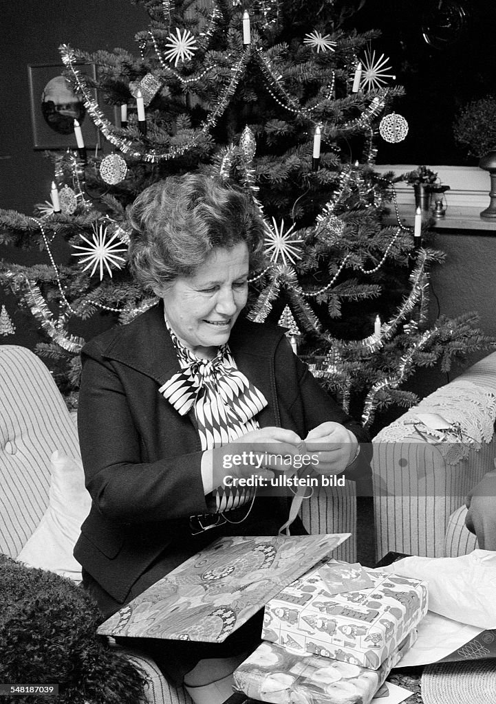 Christmas, Christmas Eve, older woman on unpacking the Christmas presents, in the background the Christmas tree, aged 60 to 70 years, Frieda - 24.12.1979