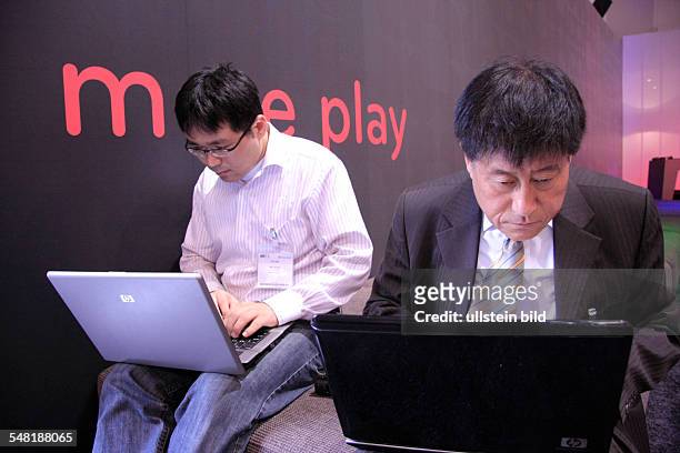 Germany - Berlin - Berlin: International Consumer Electronics Trade Show IFA Berlin 2008, Asian visitors with laptop in front of the lettering "more...