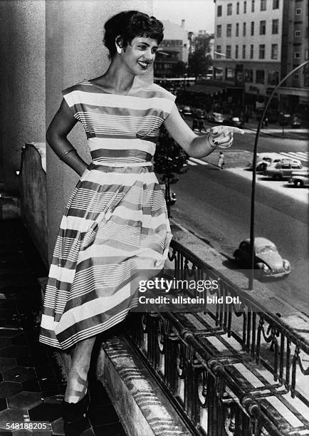 Eskens, Margot *- Schlagersaengerin, D - Ganzkoerperaufnahme, sitzt im Sommerkleid auf einer Balkonbruestung und deutet auf etwas - 1957