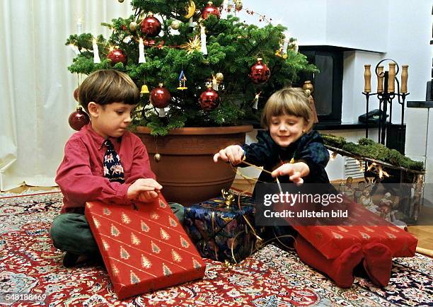 Kinder packen Geschenke unterm Weihnachtsbaum aus - 1996