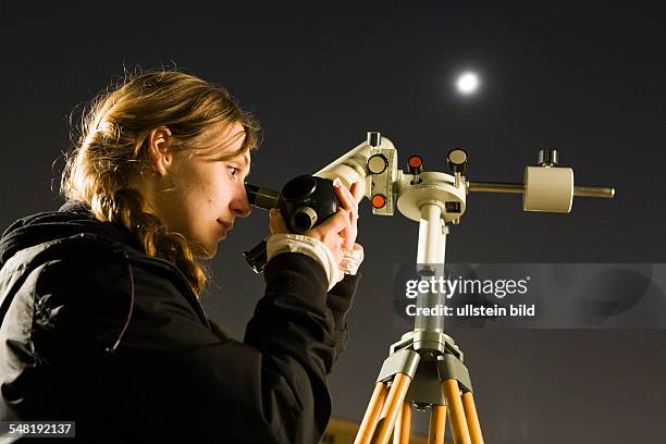 Kerstin Krueger beobachtet den Mond durch ein Linsenteleskop. | DEU, Germany 03.2009: Young amateur astronomer on a school yard in Lichtenberg...