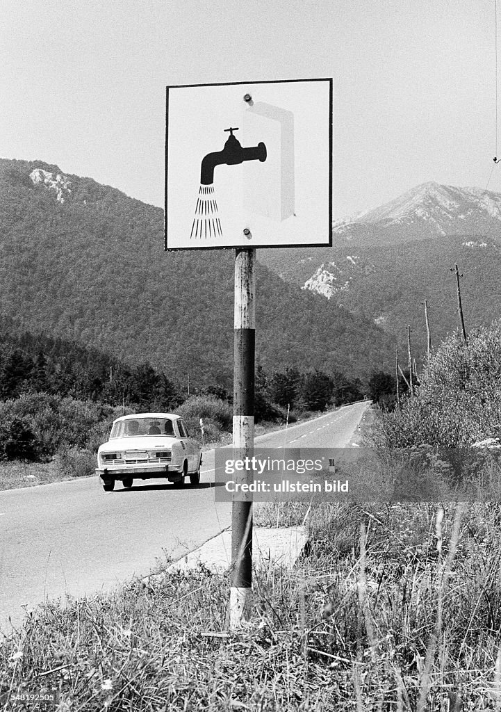 Car drives on a country road through the Velebit mountains, a signboard at the roadside leads to the next resting place with washing option, Croatia, at that time Jugoslavia, Yugoslavia - 15.08.1974