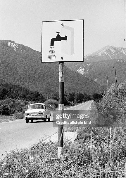 Car drives on a country road through the Velebit mountains, a signboard at the roadside leads to the next resting place with washing option, Croatia,...