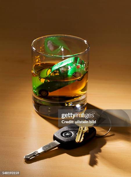 Car key and model of a car in a glass with alcohol
