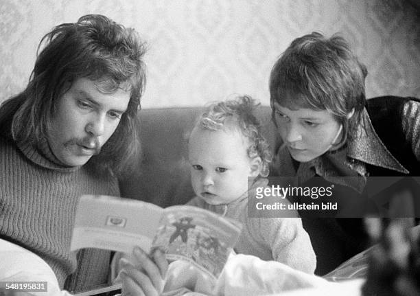 People, young family, parents read from a picture-book to their child, man, aged 20 to 28 years, woman, aged 20 to 25 years, girl, aged 2 to 3 years,...