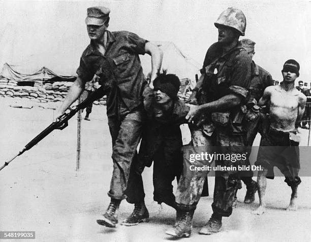 Vietnam War US-soldiers marching off 2 captured Vietcong. Near Tan Ki at the Ly River