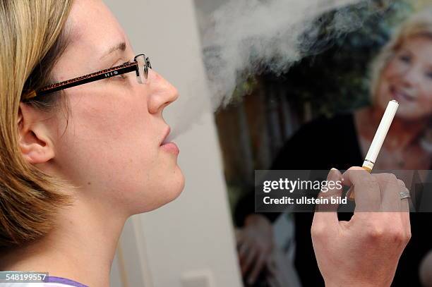 Woman is smoking an electrical cigarette which is belching water vapour instead of unhealthy smoke -