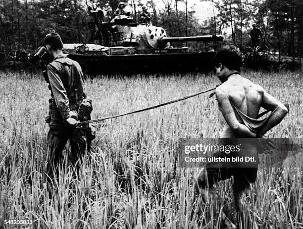 Vietnam War US-soldier marching off a captured Vietcong on a leash Area of Da Nang
