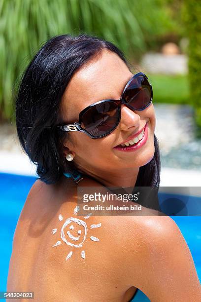 Symbolic photo sunprotection, woman at the pool with suncream