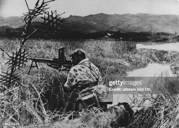 French paratrooper takes position with his machine gun shortly after landing; the paratroops were deployed behind the lines of the Viet Minh to...