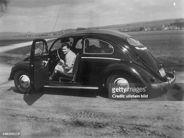 Junge Frau schaut aus einem VW-Käfer - 1955