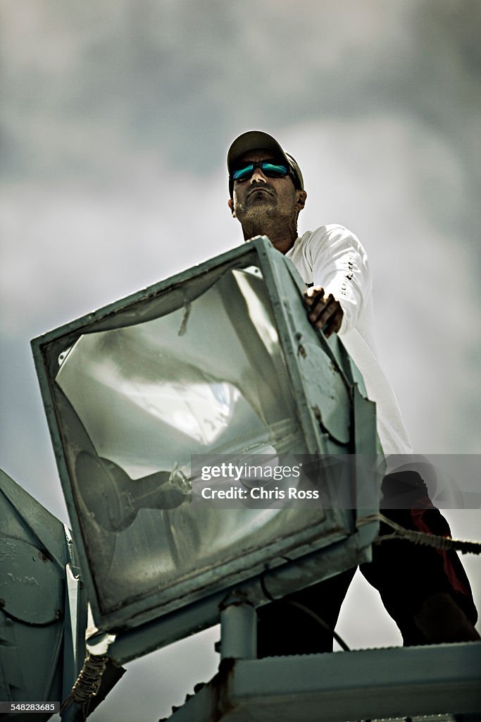 An expedition crew member adjusts boat light